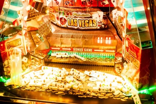 Värikäs Las Vegas -teemainen peliautomaatti, jonka tasolla on kolikoita ja pelikortteja.
